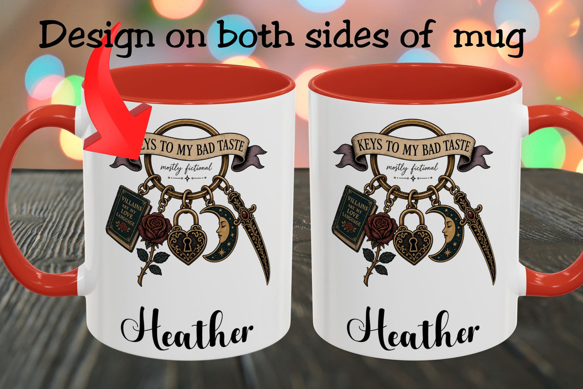 Two white ceramic mugs with red interiors and red handles are shown side by side on a wooden surface with colorful blurred lights in the background. Black text at the top reads 'Design on both sides of mug,' and each mug features a printed graphic with the phrase 'Keys to my bad taste' and the name 'Heather' in script.
