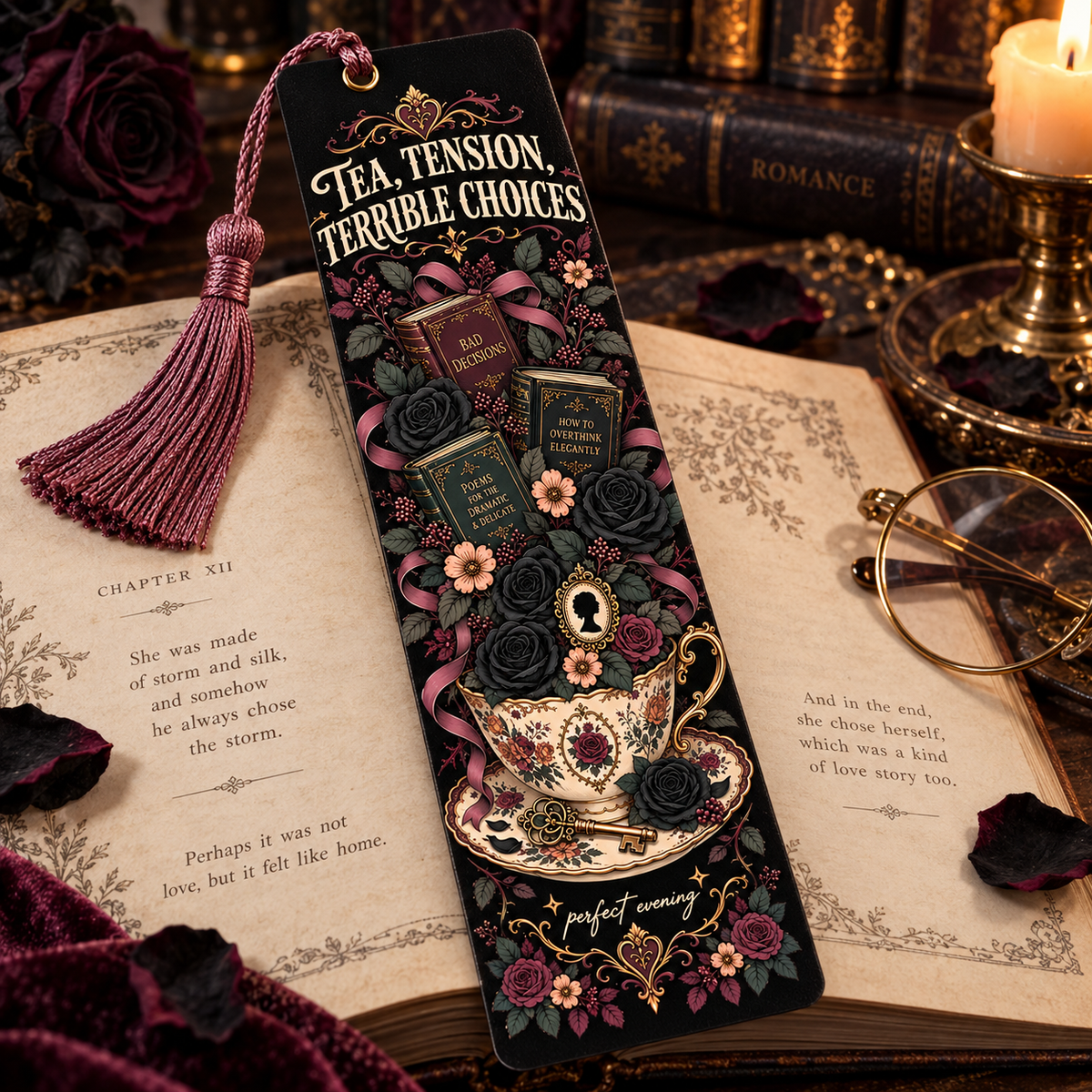 A decorative black bookmark with a tassel, featuring gothic floral artwork and the phrase 'TEA, TENSION, TERRIBLE CHOICES,' styled on open vintage books with a rose, glasses, and candle in a moody tabletop setting.