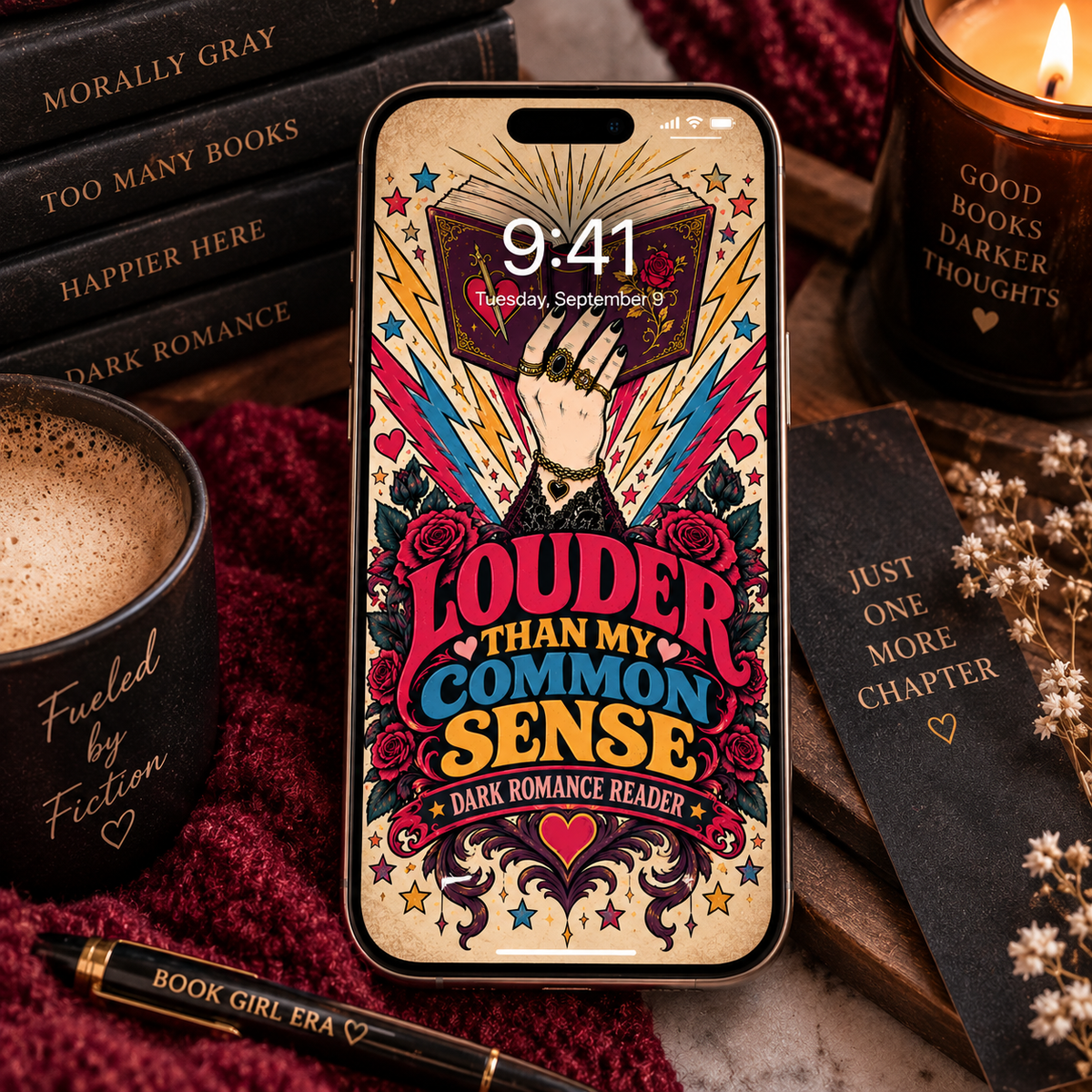 A smartphone case or phone skin featuring a dark romance-themed graphic design with the text 'LOUDER THAN MY COMMON SENSE' and 'DARK ROMANCE READER,' shown on a phone surrounded by books, a candle, and a cup on a styled tabletop.