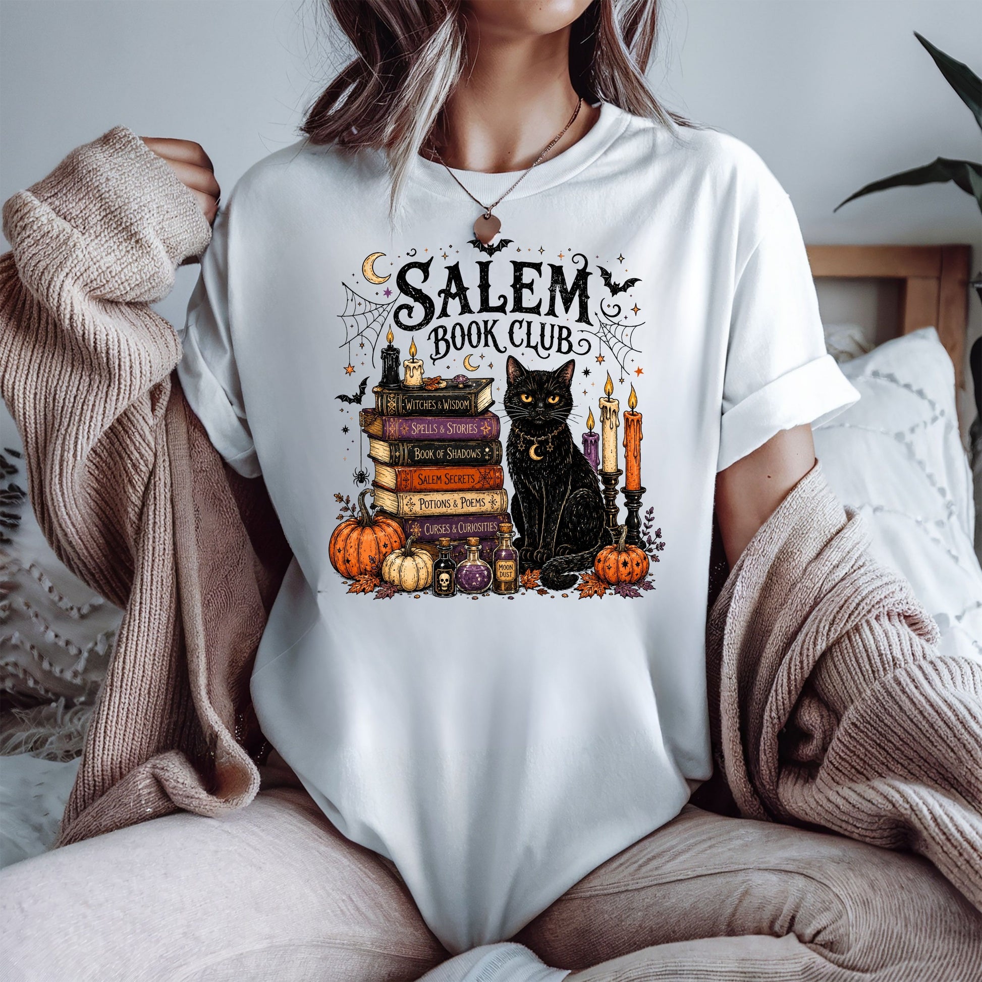 Calling all spooky readers! 🖤📚 The Salem Book Club shirt is the perfect Halloween tee for book lovers who can't resist black cats, witchy vibes, candlelit reading nights, and magical stories. Featuring a charming black cat, vintage spell books, pumpkins, potion bottles, spider webs, bats, and cozy autumn details, this Comfort Colors shirt is made for BookTok fans, book club meetings, bookstore visits, Halloween parties, and all your fall adventures. A fun gift for readers, librarians, teachers, fantasy lo