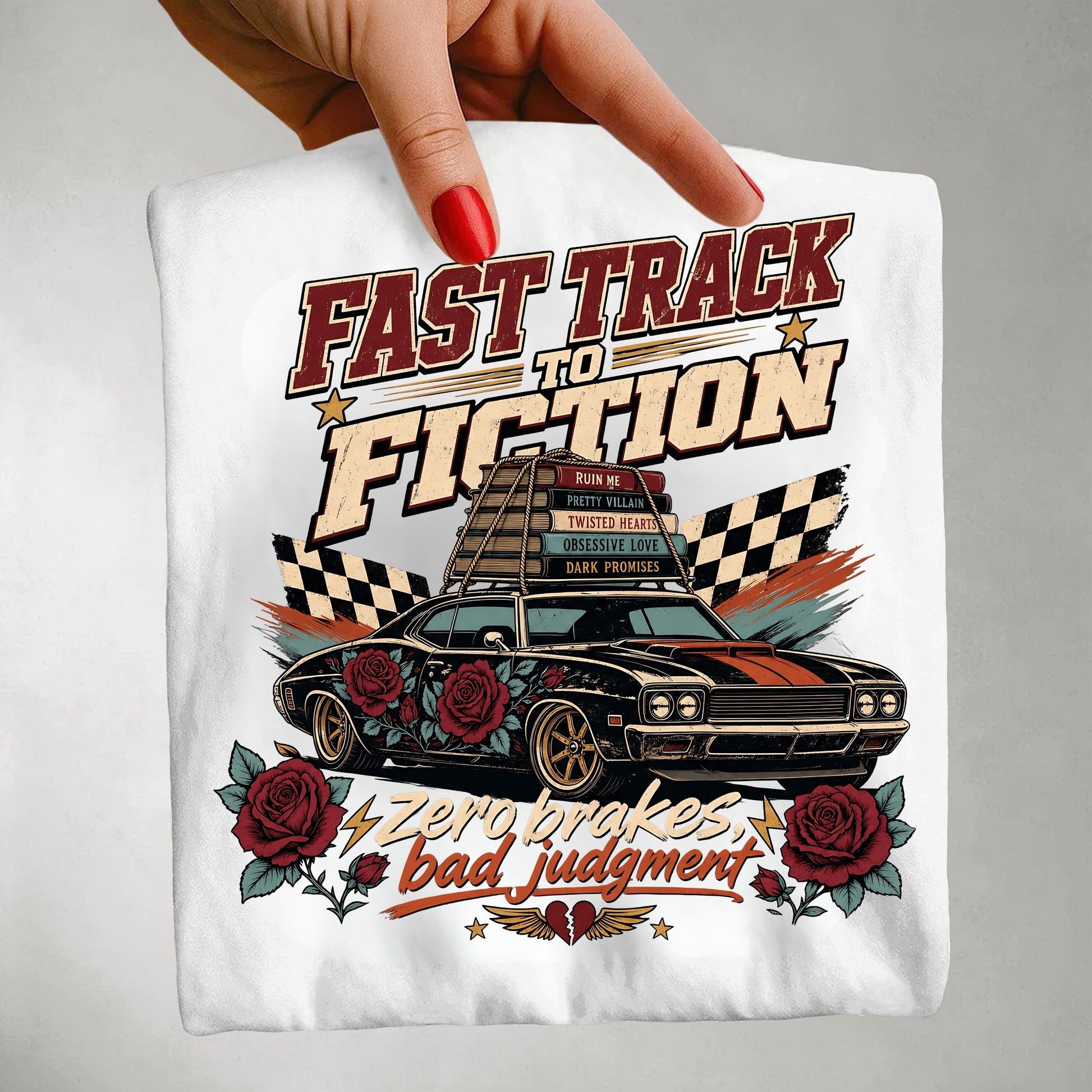 A hand with red nail polish holds up a white t-shirt featuring a retro-style graphic of a black muscle car with red roses, checkered flags, and the text 'FAST TRACK TO FICTION' and 'Zero makes bad judgment'.