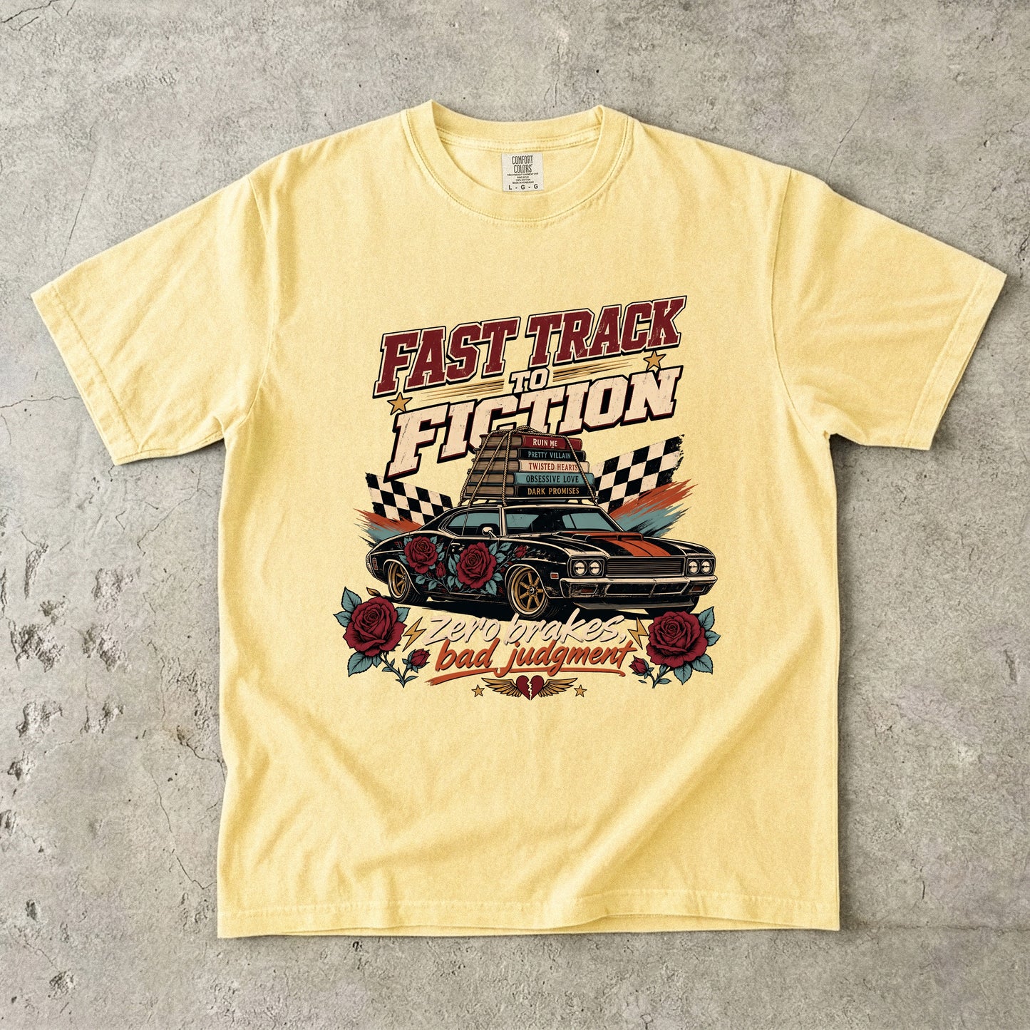 A pale yellow graphic t-shirt laid flat on a textured gray concrete surface. The shirt features a retro-style racing graphic with the text 'FAST TRACK TO FICTION' and 'bad judgment' in red, black, and white, surrounding an illustration of a classic muscle car with roses and checkered flags.