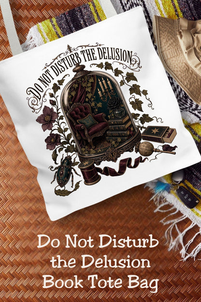 Physically here, mentally in a candlelit library. This “Do Not Disturb the Delusion” book tote features a miniature reading nook beneath a glass dome, surrounded by ivy, moody flowers, and burgundy ribbon. The 16 × 16-inch bag holds your current read and everyday essentials for library trips and bookstore browsing. A thoughtful gift for romantasy readers, dark academia fans, and book lovers who treasure uninterrupted reading time.