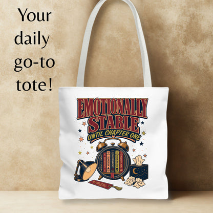 A white canvas tote bag with a vintage-style graphic reading 'EMOTIONALLY STABLE UNTIL CHAPTER ONE' and illustrated book, lamp, and tissue box elements, shown against a textured beige background with the text 'Your daily go-to tote!' on the left.