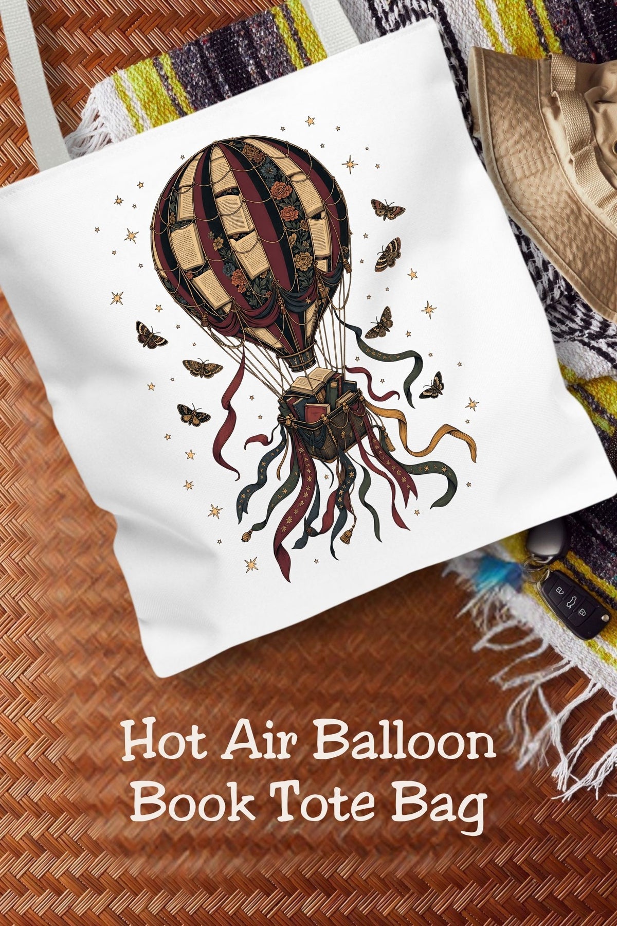 Let your next chapter take you somewhere new. This hot air balloon book tote features vintage book-page panels, florals, and a basket filled with books, surrounded by flowing ribbons, moths, and stars. The 16 × 16-inch bag carries your current read and everyday essentials for library trips and bookstore browsing. A thoughtful gift for book lovers, fantasy readers, and fans of whimsical dark academia style.