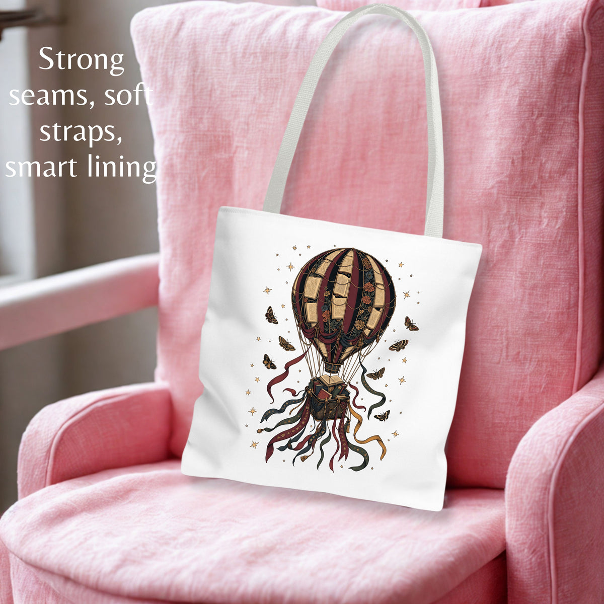 A white canvas tote bag with a whimsical hot air balloon illustration, resting on a pink armchair. The text on the left highlights its strong seams, soft straps, and smart lining.
