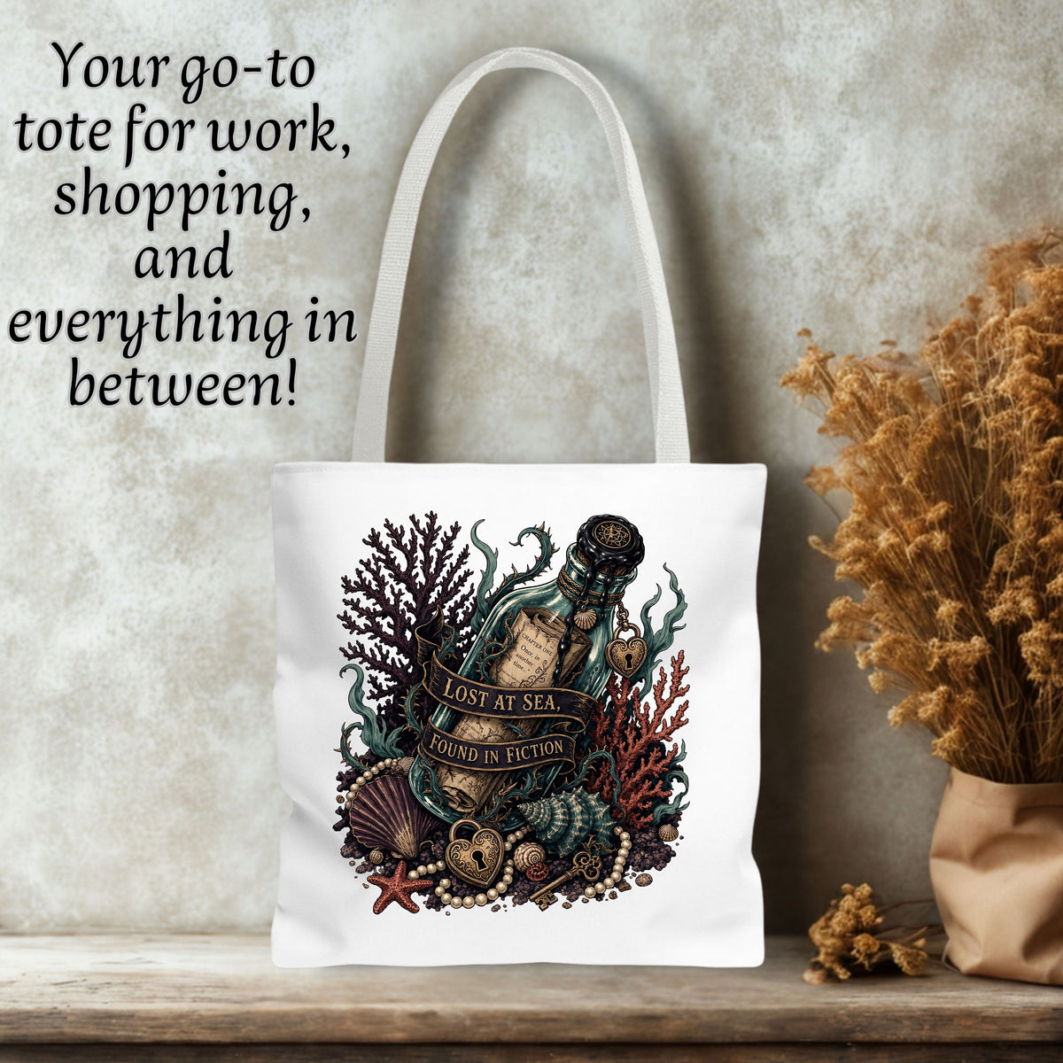 A white canvas tote bag with a detailed nautical illustration of a bottle 'Lost at Sea' surrounded by coral, shells, and a starfish. The bag is displayed on a wooden shelf next to dried flowers, with a textured gray wall background and black text on the top left that reads, 'Your go-to tote for work, shopping, and everything in between!'.