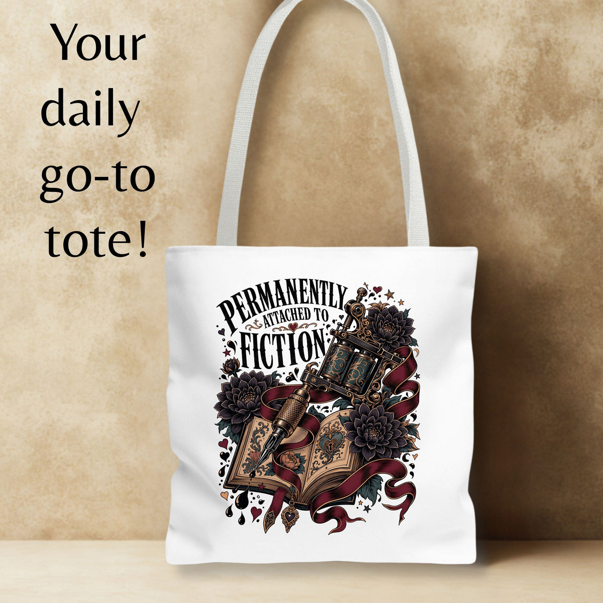 A white canvas tote bag with a gothic-style graphic print featuring an open book, lantern, roses, and the text 'PERMANENTLY ATTACHED TO FICTION'. The bag is shown against a textured beige background with a text overlay on the left reading 'Your daily go-to tote!'.