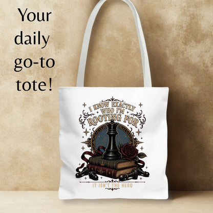 A white canvas tote bag with a dark fantasy-themed graphic print featuring a chess piece, books, a rose, and decorative text, displayed against a textured beige background with promotional text on the left.