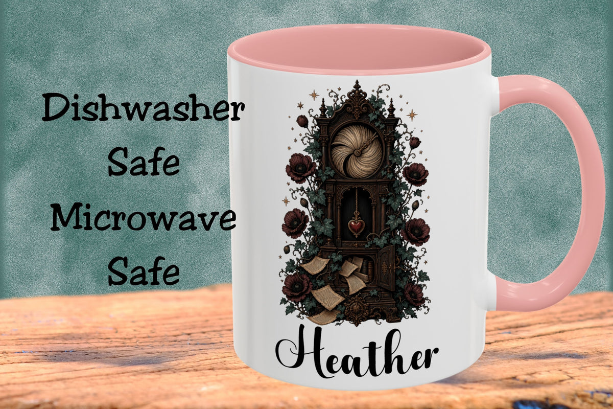 A white ceramic mug with a pink handle and interior, featuring a gothic-style illustration of a clock tower surrounded by roses and the name 'Heather' printed below. The mug is shown on a wooden surface against a textured teal background with text reading 'Dishwasher Safe Microwave Safe'.