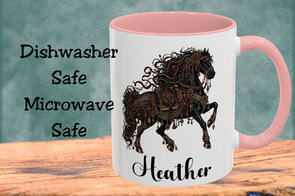 A white ceramic mug with a pink handle and interior, featuring a dark brown steampunk horse illustration and the name 'Heather' printed on the front. The mug is displayed on a wooden surface against a textured teal background with text reading 'Dishwasher Safe Microwave Safe'.