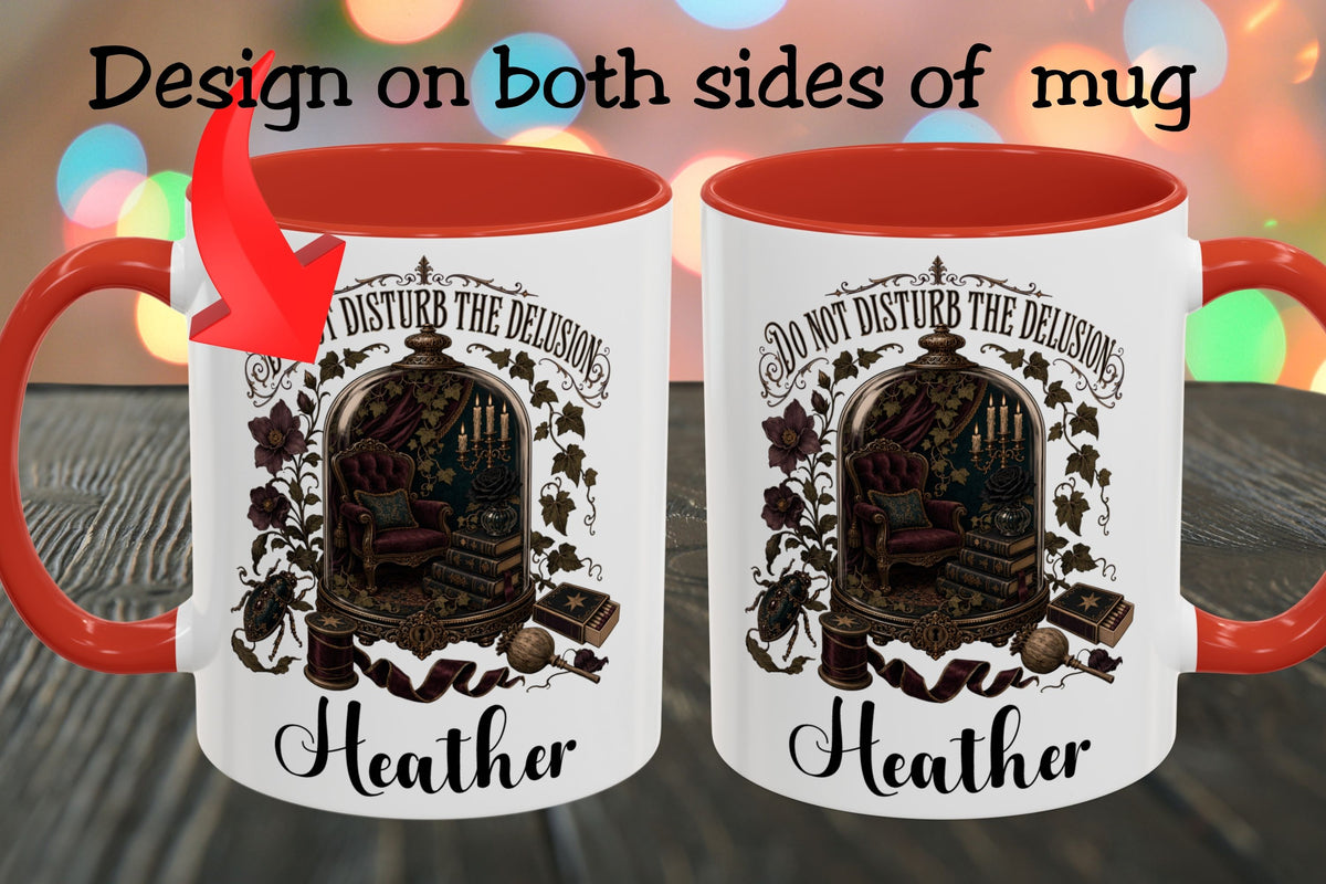 Two white ceramic mugs with red interiors and handles are shown side by side on a dark wooden surface with colorful blurred lights in the background. Black text at the top reads 'Design on both sides of mug,' and each mug features a gothic illustration of an ornate chair inside an arched frame with the text 'Do not disturb the delusion' and the name 'Heather' below.