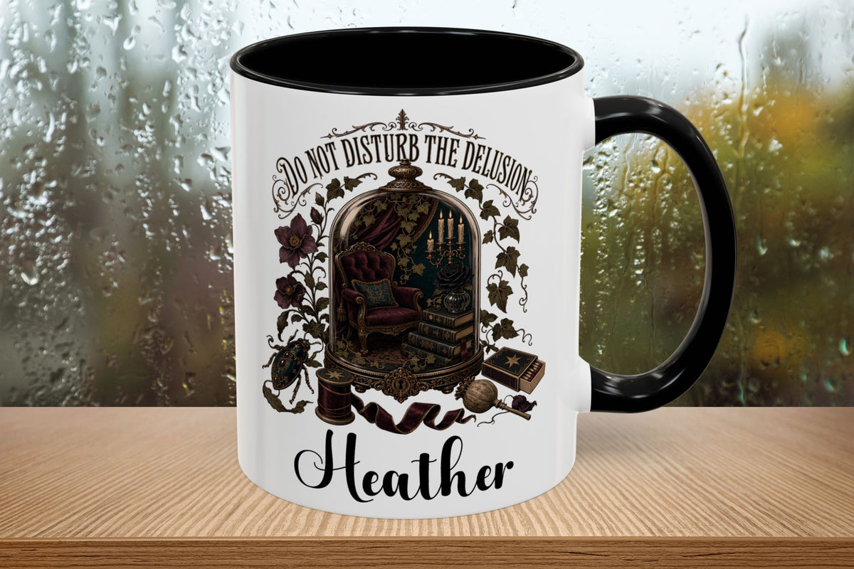 A white ceramic mug with a black interior and black handle, featuring a vintage-style illustration of a library scene with the text 'DO NOT DISTURB THE DELUSION Heather' on a wooden surface with a blurred rainy window background.