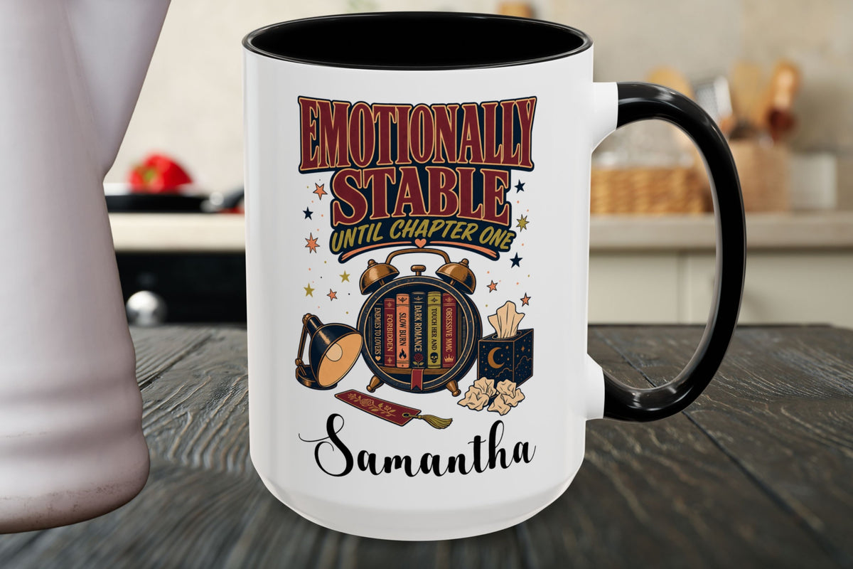 A white ceramic mug with a black handle and interior, featuring a colorful graphic that reads 'Emotionally Stable Until Chapter One' and the name 'Samantha' on a dark wooden tabletop.
