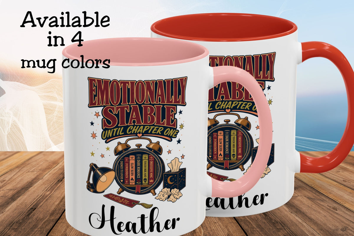 Two personalized ceramic mugs with a white exterior, pink interior, and pink handles, displayed on a wooden surface with a beach background. The mugs feature a graphic design with the text 'EMOTIONALLY STABLE UNTIL CHAPTER ONE' and the name 'Heather'.