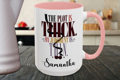 A white ceramic mug with a pink handle and interior, featuring a printed quote that reads 'THE PLOT IS THICK. MY JUDGMENT IS THIN.