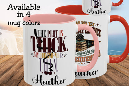 Three ceramic mugs shown on a wooden surface with a blurred beach background. The mugs are white with pink interiors and handles, and one mug has a red handle.