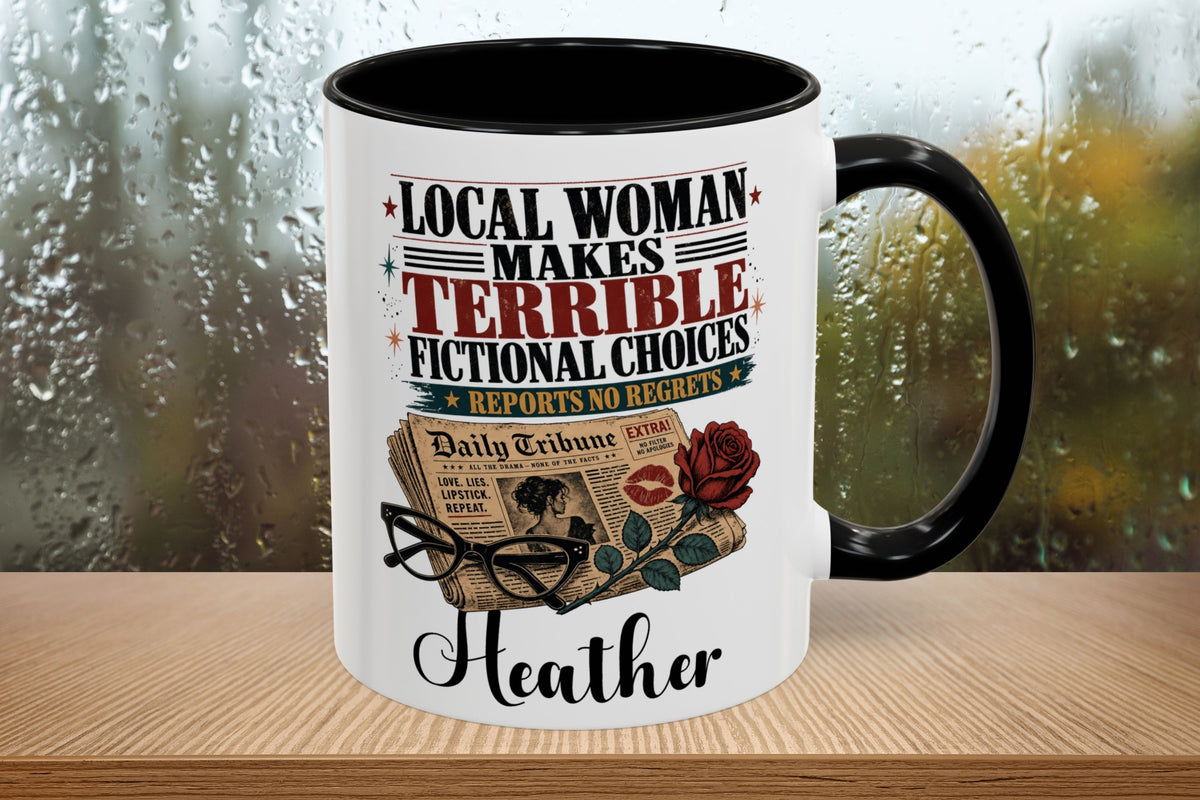 A white ceramic mug with a black handle and black interior, printed with the phrase 'LOCAL WOMAN MAKES TERRIBLE FICTIONAL CHOICES REPORT SAD REPORTS' above an illustration of a newspaper, eyeglasses, a red rose, and the name 'Heather'. The mug sits on a wooden surface with a blurred rainy window background.