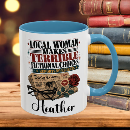 A white ceramic mug with a bright blue interior and handle, printed with the phrase 'LOCAL WOMAN MAKES TERRIBLE FICTIONAL CHOICES REPORTS NO REGRETS' and a vintage newspaper, rose, glasses, and lipstick motif, with the name 'Heather' at the bottom. The mug is shown on a wooden surface with a stack of old books and warm blurred lights in the background.