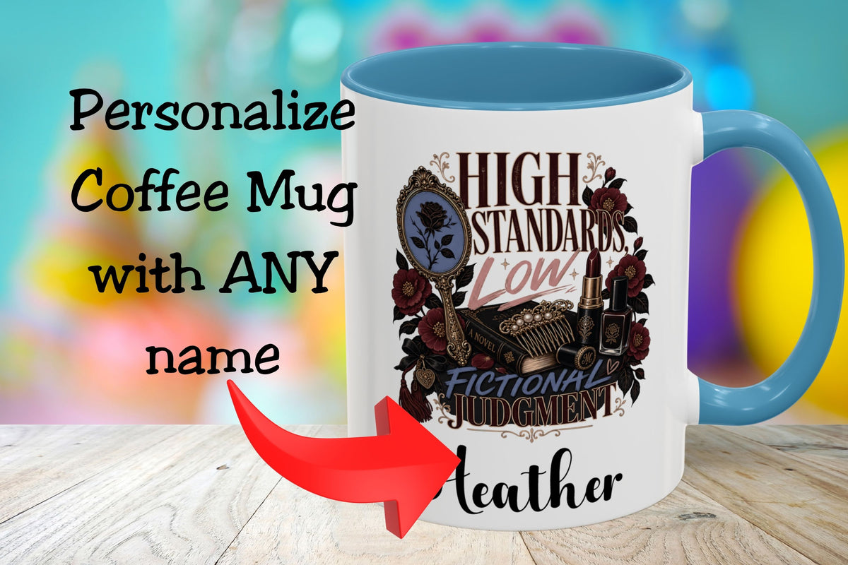 A white coffee mug with a blue handle and blue interior, printed with decorative text and illustration reading 'HIGH STANDARDS LOW FICTIONAL JUDGMENT' and 'Leather.' Large overlaid text says 'Personalize Coffee Mug with ANY name' with a red arrow pointing to the mug.