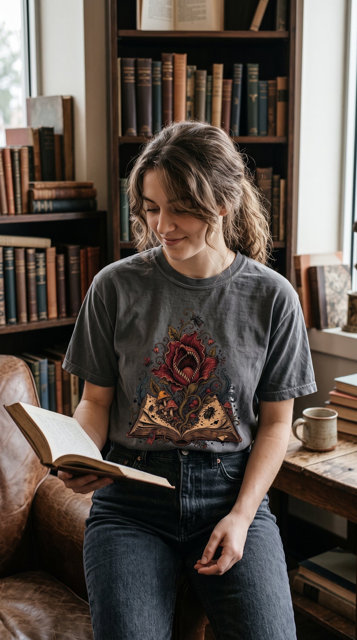 Add a little danger to your bookish wardrobe with this gothic book lover shirt featuring a fierce carnivorous flower growing from an antique open book. Surrounded by mushrooms, insects, curling vines, and dark botanical details, this fantasy reader tee is perfect for bookstore trips, book club, library days, or gifting to a dark academia fan. Available in Blue Jean, Moss, Pepper, Butter, Espresso, Ivory, and White. #BookLoverShirt #GothicStyle #DarkAcademia #FantasyReader #BookishGift
