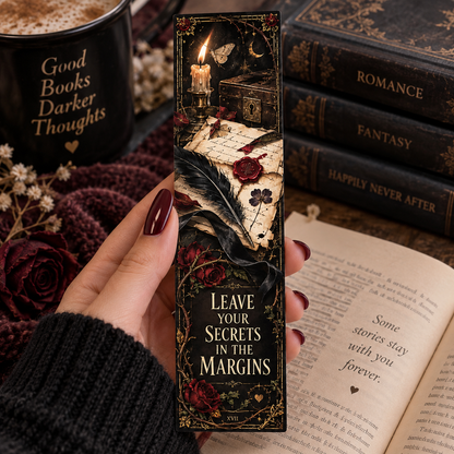 A hand with dark red nail polish holds a gothic-style bookmark featuring an illustration of a burning candle, feather quill, vintage letter, and red roses on a black background. The bookmark has the text 'LEAVE YOUR SECRETS IN THE MARGINS' and the number '2911'.